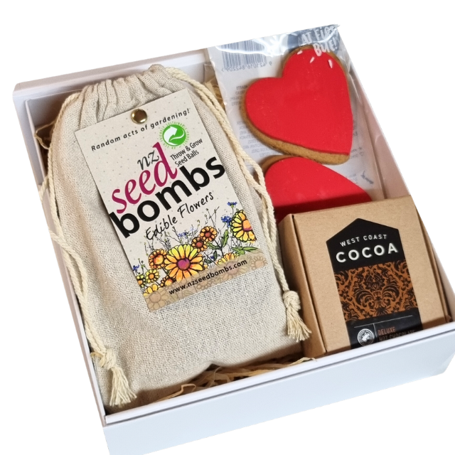 Gift box on white background with Edible Flower Seed Bombs, heart cookies and West Coast Cocoa